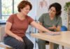 Exercice doux de mobilité de l’épaule sur une table lors d’une réadaptation après chirurgie mammaire.