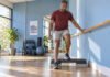 Homme effectuant un exercice contrôlé sur une marche basse avec appui sur une barre.